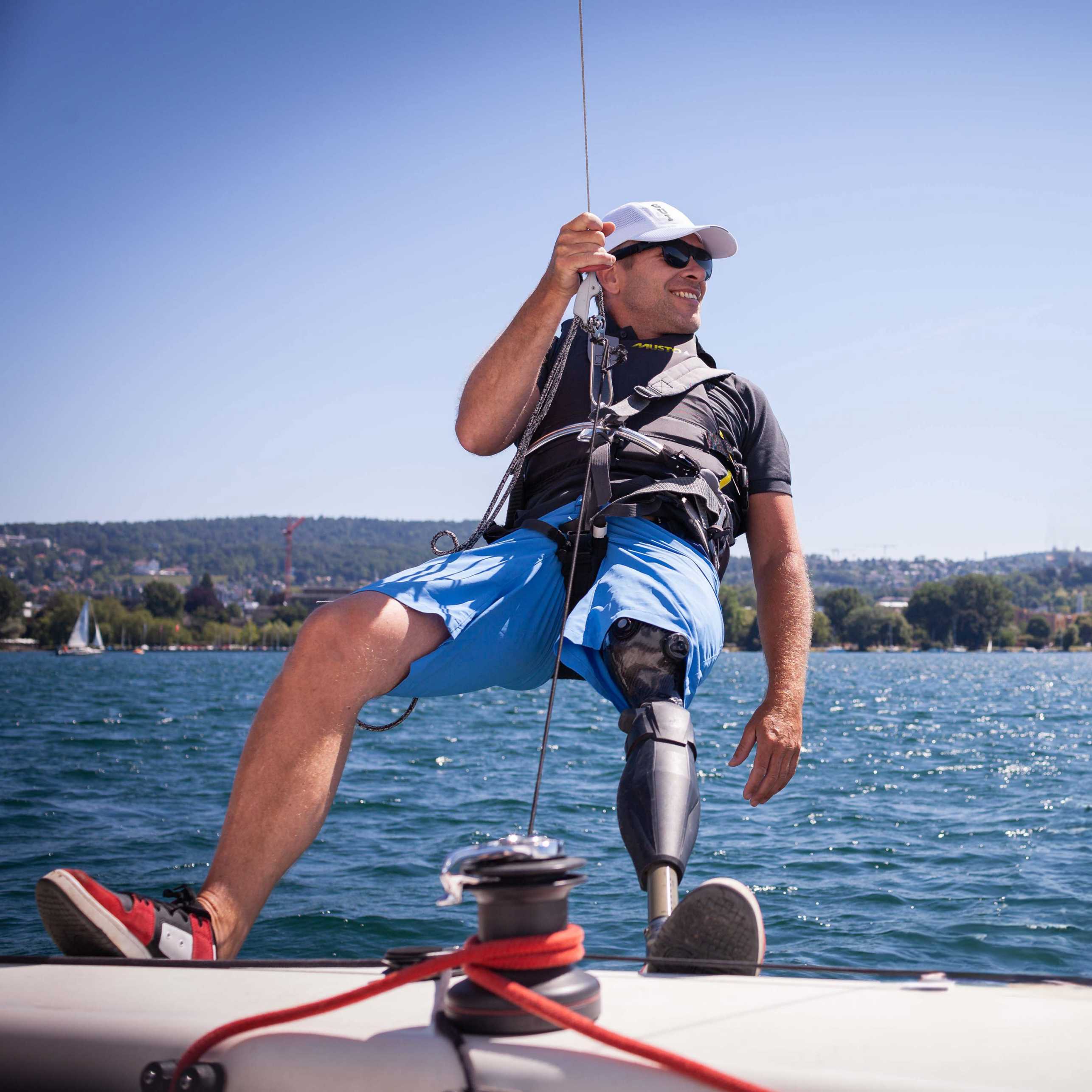 Enlarged view: Filip Pockelé with prosthetic leg hangs sideways from sailboat in trapeze