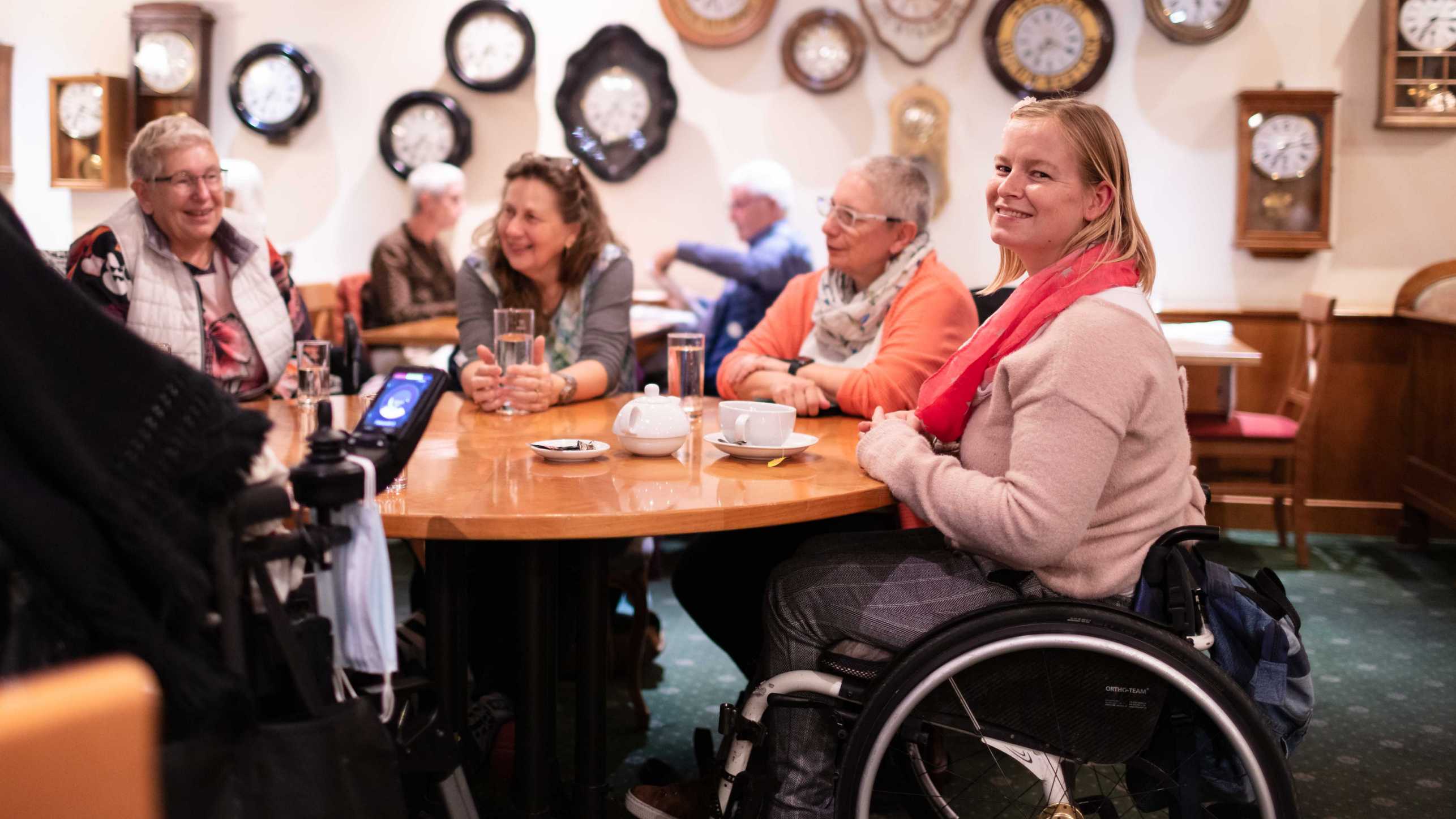 Enlarged view: Linda Halter wheelchair sits at a round table with friends and discusses