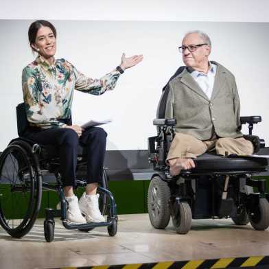  Rubina Meixgerand Christian Lohr on stage. Both are sitting in wheelchairs