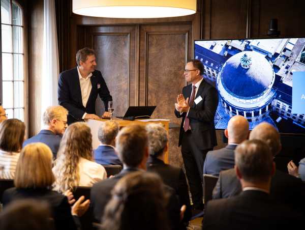 Enlarged view: Two speakers discuss in front of a seated audience