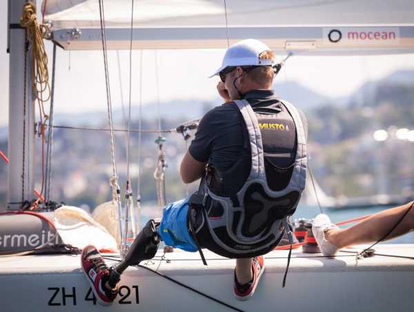 Filip Pockelé with prosthetic leg hangs sideways from sailboat in trapeze