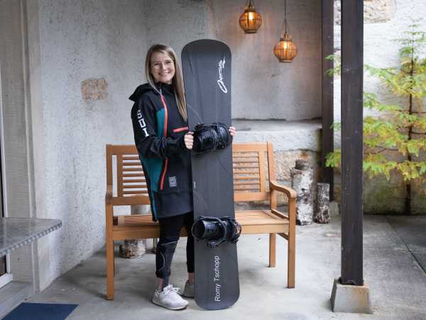 Enlarged view: Romy Tschopp standing with snowboard in front of a bench