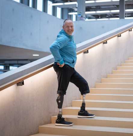 Enlarged view: Rüdiger Böhm with two prosthetic legs poses on long staircase