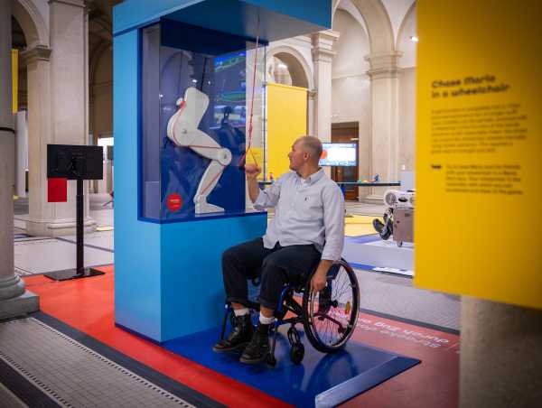 Person in a wheelchair at an exhibit showing the function of an exoskeleton