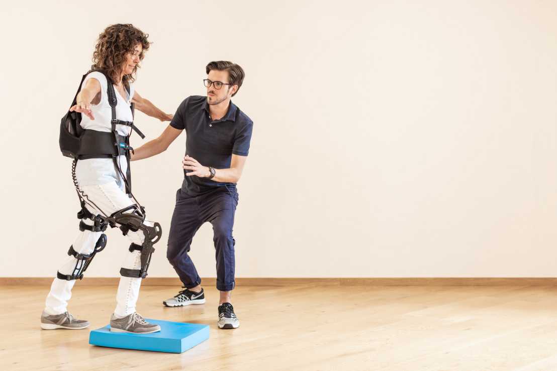 Enlarged view: Physiotherapist cares for patient wearing a soft exoskeleton