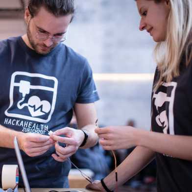 Two people handle electronics components at hackahealth event