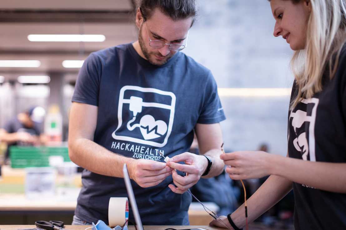 Enlarged view: Two people handle electronics components at hackahealth event