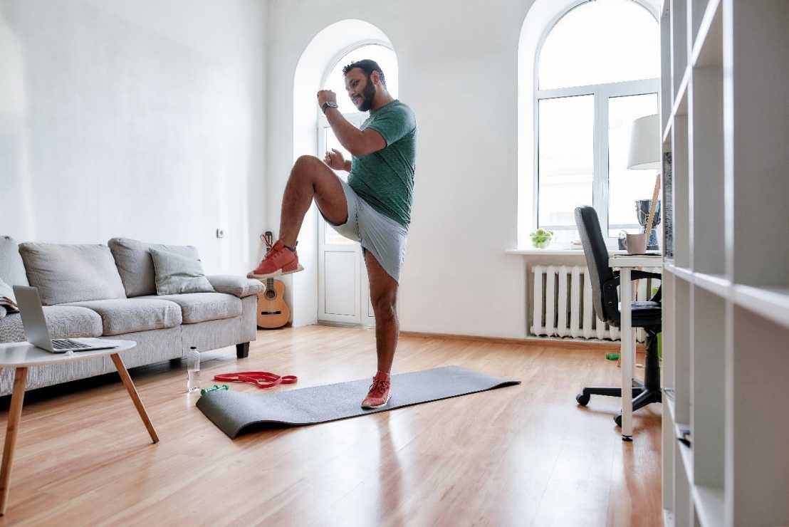 Enlarged view: Man on yoga mat practicing exercises in front of a laptop