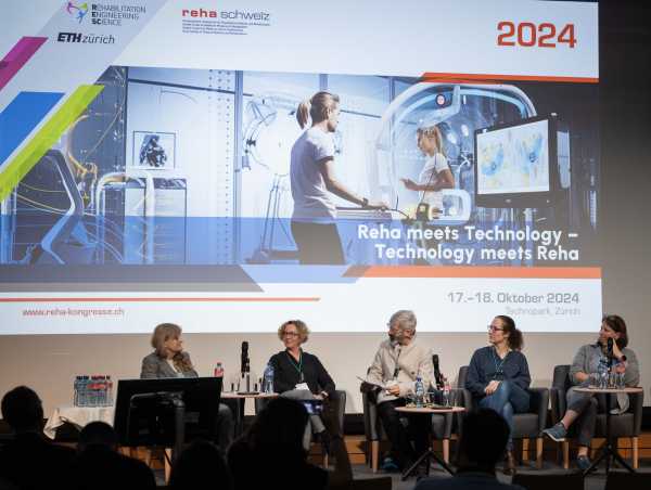 Discussion panel in front of projection with advertising for the REHA Congress 2024