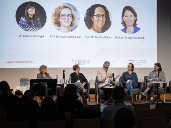 Discussion panel in front of projection with their portraits