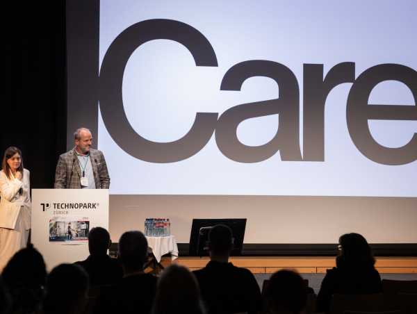 Two persons speaking in front of a presentation with the huge word 